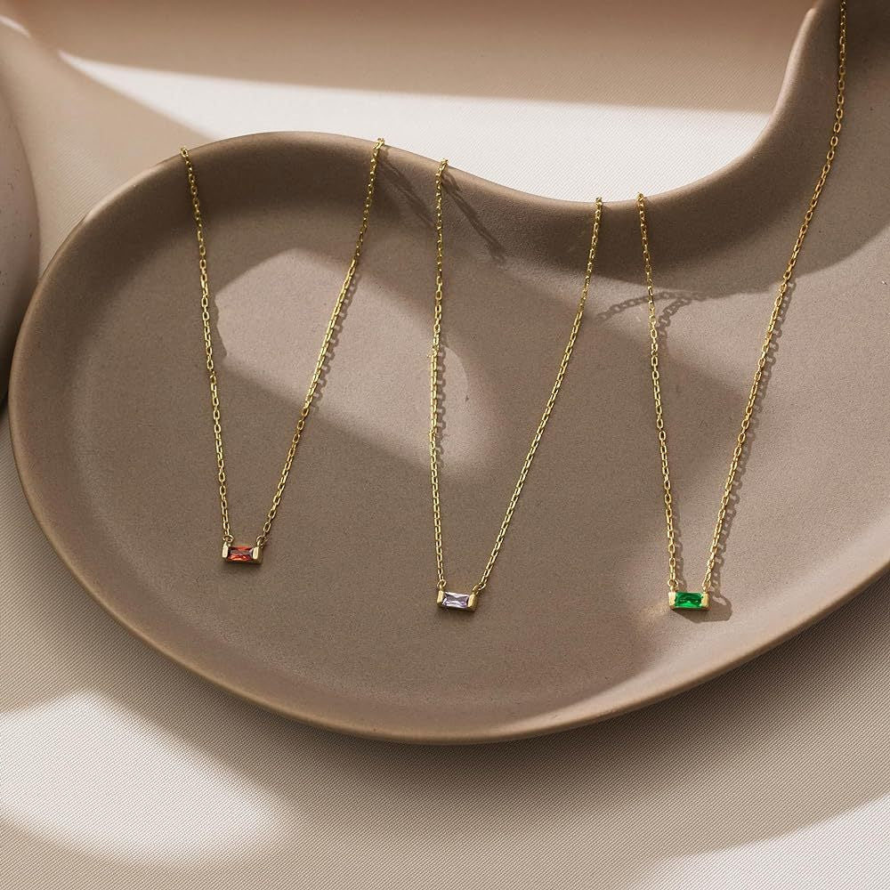 Close-up of minimalist silver clavicle chain with a sparkling square lucky stone red green and piuple