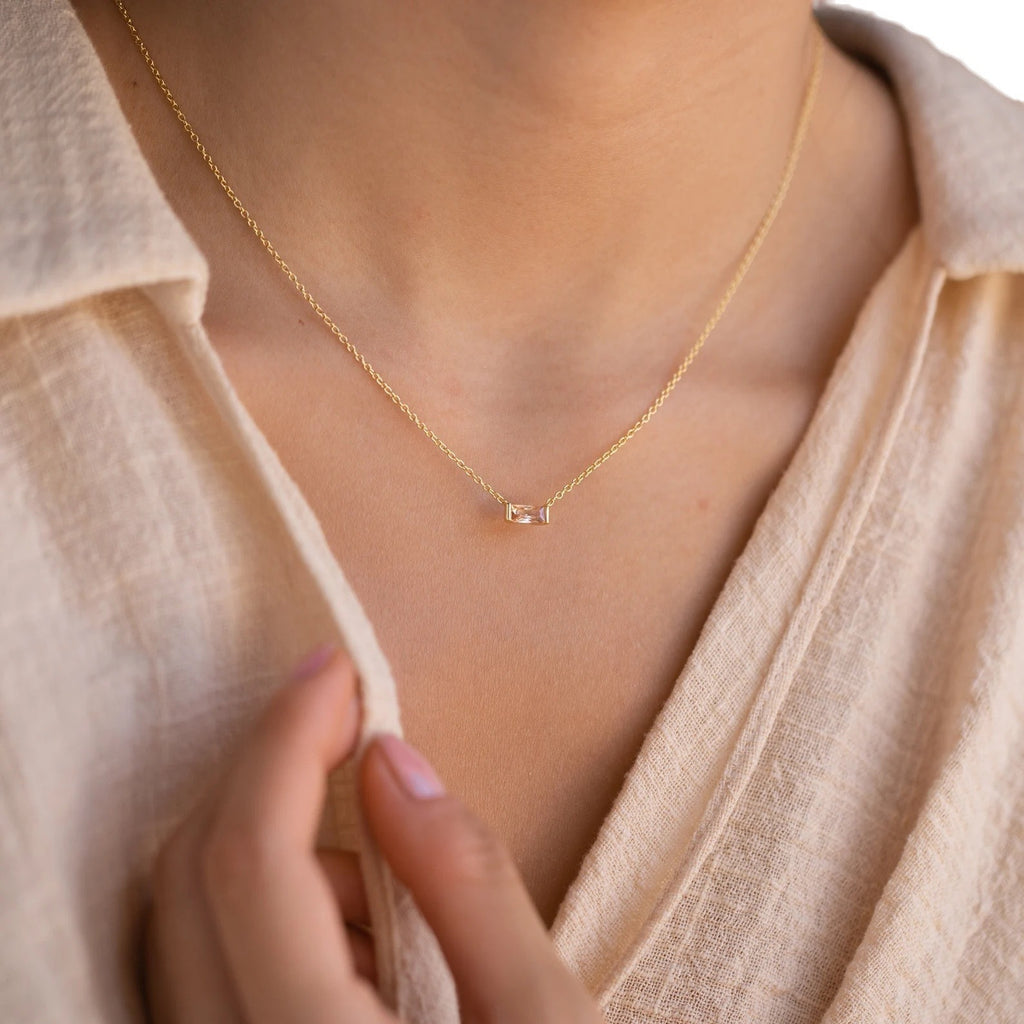 Close-up of minimalist silver clavicle chain with a sparkling square lucky stone on model
