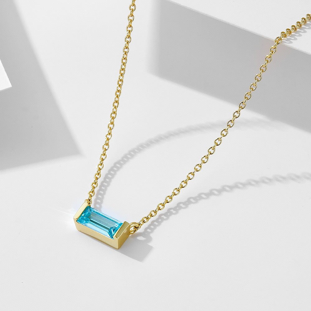 Close-up of minimalist silver clavicle chain with a sparkling square lucky stone