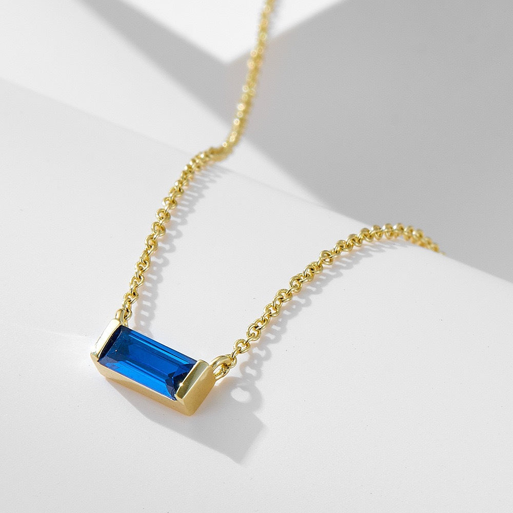 Close-up of minimalist silver clavicle chain with a sparkling square lucky stone
